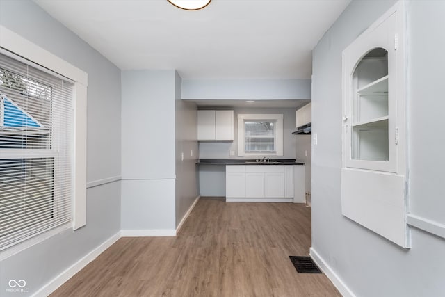 kitchen featuring light hardwood / wood-style flooring, white cabinets, and sink