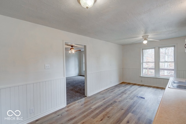 spare room featuring ceiling fan, light wood-type flooring, and a textured ceiling