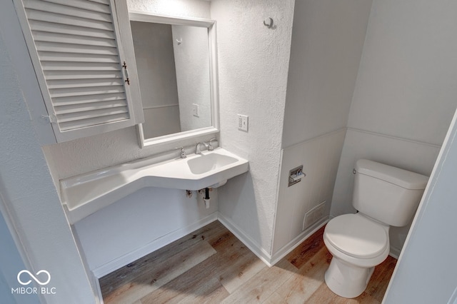 bathroom with sink, toilet, and hardwood / wood-style flooring