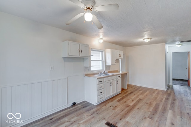 kitchen with white cabinets, sink, light hardwood / wood-style floors, a textured ceiling, and ceiling fan