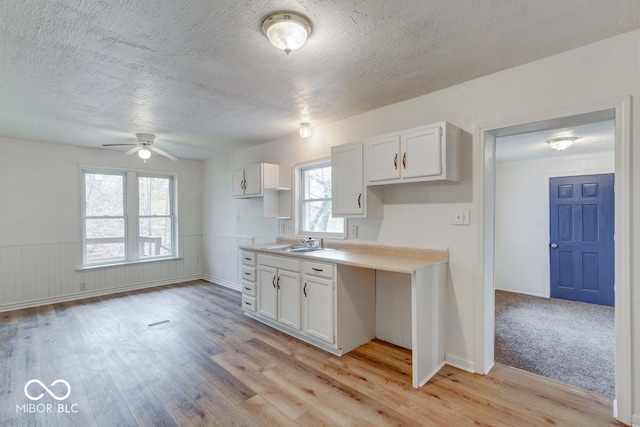 kitchen featuring light hardwood / wood-style flooring, white cabinets, ceiling fan, and sink