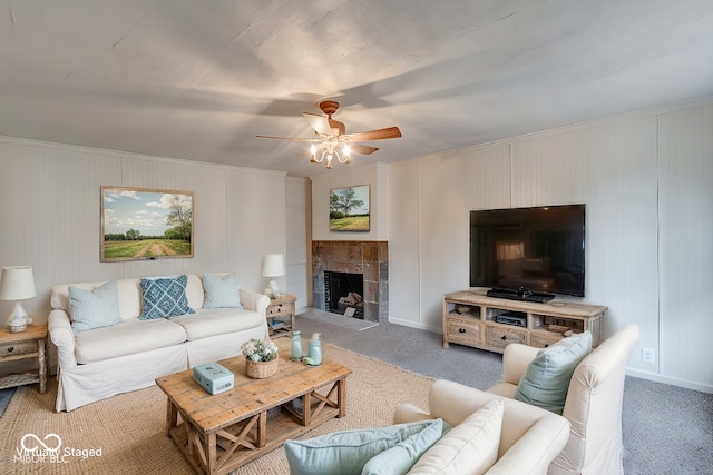 carpeted living room with a tile fireplace, ceiling fan, and crown molding