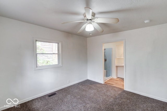 carpeted spare room featuring ceiling fan and a textured ceiling