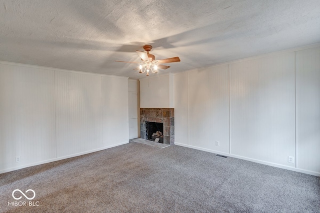 unfurnished living room featuring ceiling fan, a fireplace, carpet floors, and a textured ceiling