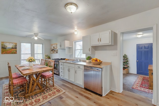 kitchen with appliances with stainless steel finishes, white cabinetry, plenty of natural light, and ceiling fan