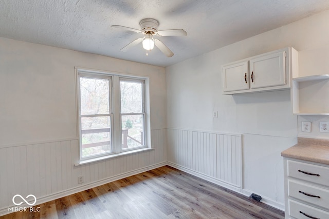 interior space featuring ceiling fan, light hardwood / wood-style floors, and a textured ceiling