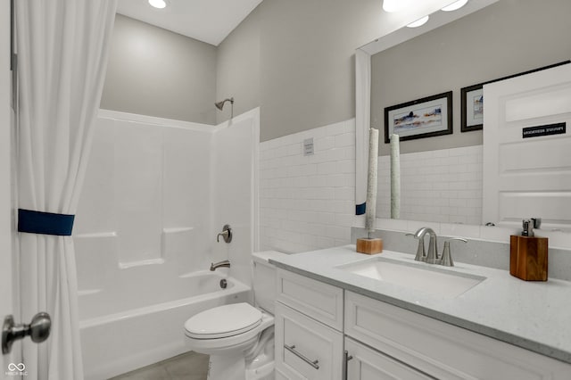 full bathroom featuring shower / bathtub combination with curtain, tile patterned flooring, toilet, vanity, and tile walls