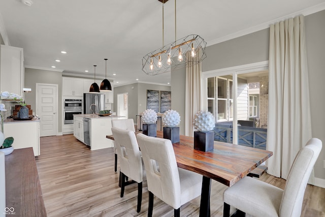 dining room featuring light wood-type flooring, ornamental molding, sink, and an inviting chandelier