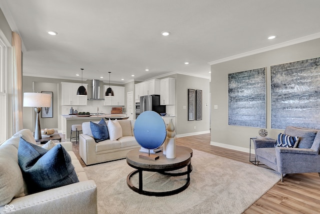 living room featuring crown molding, light wood-type flooring, and sink