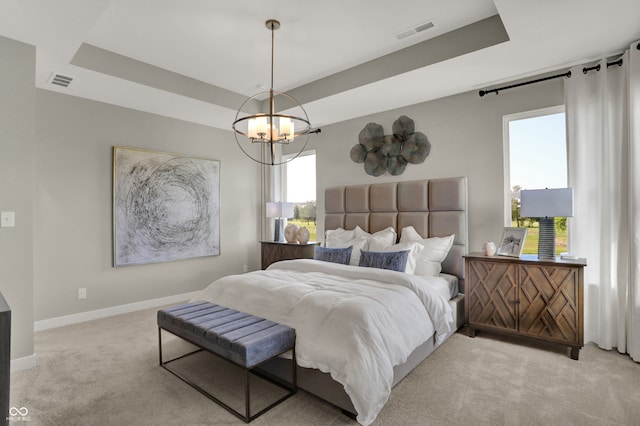 carpeted bedroom with a raised ceiling and an inviting chandelier