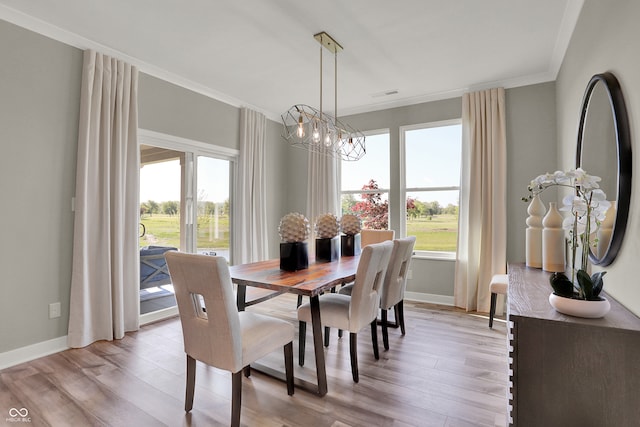 dining space featuring a chandelier, light wood-type flooring, and crown molding