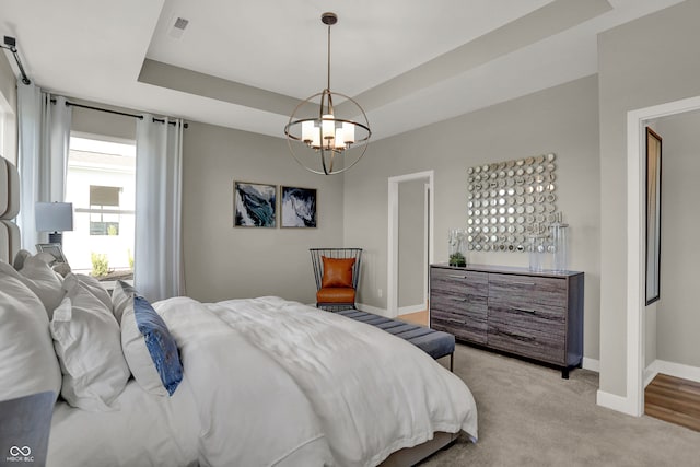 bedroom with a notable chandelier, a raised ceiling, and light carpet