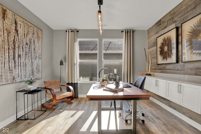 home office featuring light hardwood / wood-style floors and wooden walls