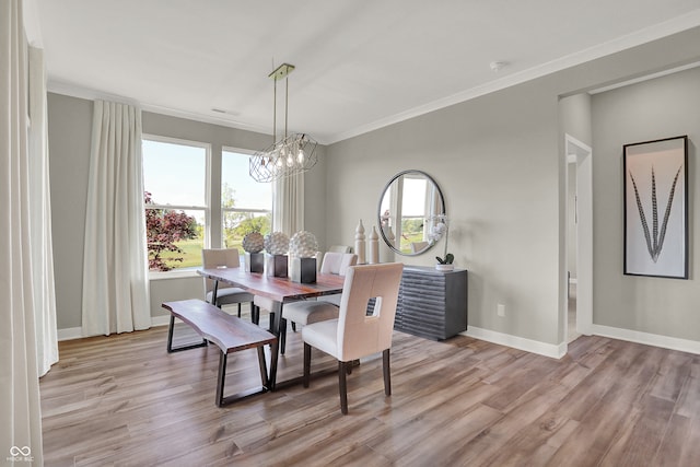 dining room featuring crown molding, light hardwood / wood-style floors, and a notable chandelier