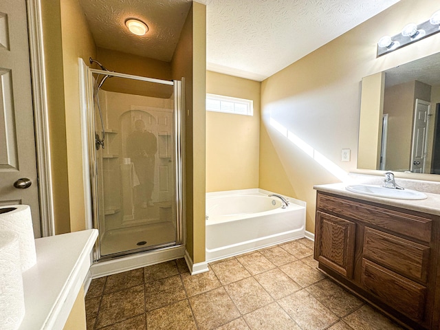 bathroom with shower with separate bathtub, vanity, and a textured ceiling