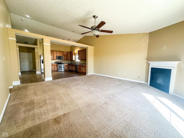 unfurnished living room featuring ceiling fan, dark carpet, vaulted ceiling, and a textured ceiling