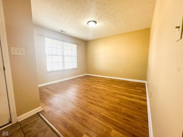 spare room with hardwood / wood-style floors and a textured ceiling