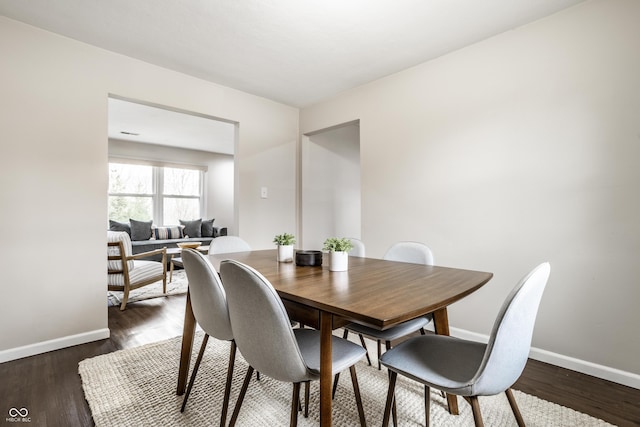 dining space featuring baseboards and dark wood-type flooring