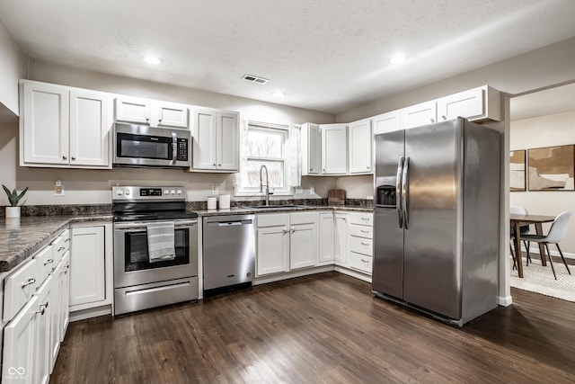 kitchen featuring dark wood-style floors, visible vents, a sink, appliances with stainless steel finishes, and white cabinetry