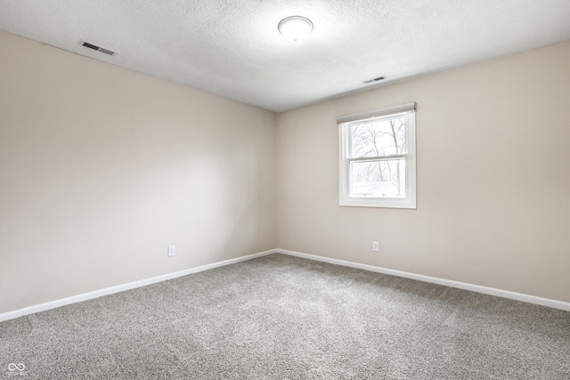 carpeted spare room with baseboards, visible vents, and a textured ceiling