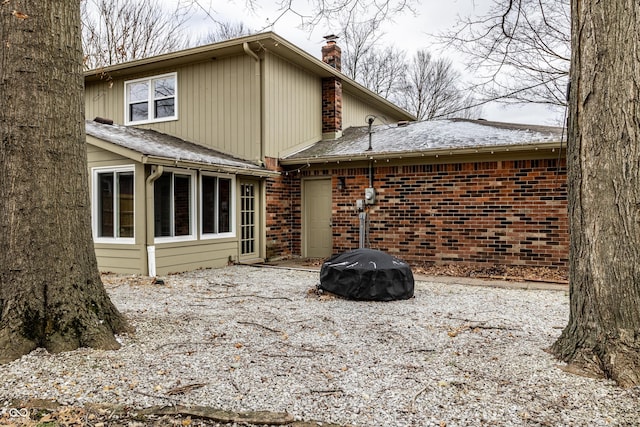 rear view of property featuring brick siding and a chimney