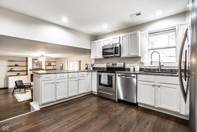 kitchen with dark wood-style floors, visible vents, a peninsula, and stainless steel appliances