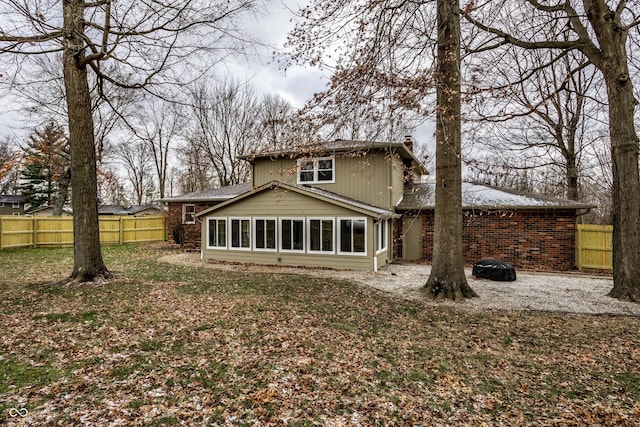 rear view of property featuring fence and brick siding