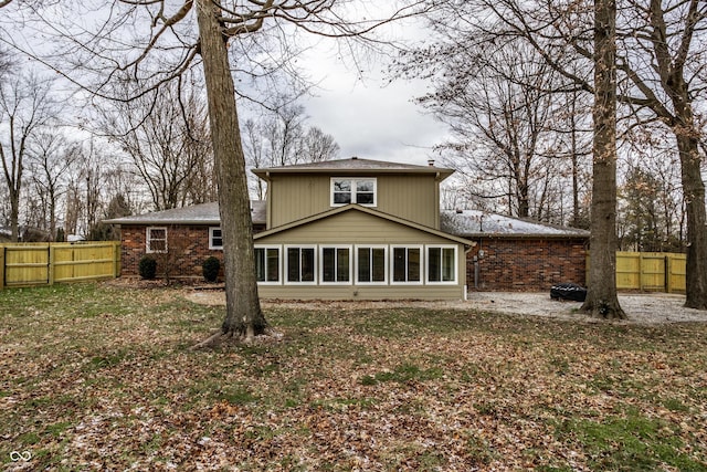 rear view of house with fence and brick siding