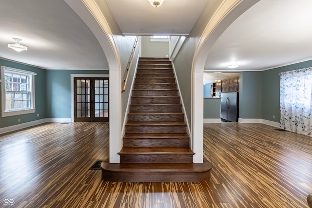 stairway featuring french doors, crown molding, and wood-type flooring