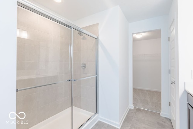 bathroom with walk in shower, vanity, and tile patterned flooring