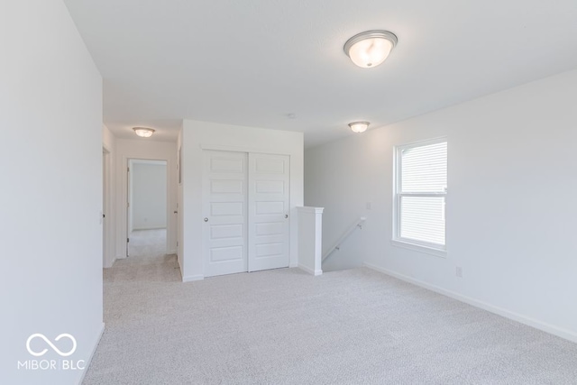 unfurnished bedroom with light colored carpet and a closet