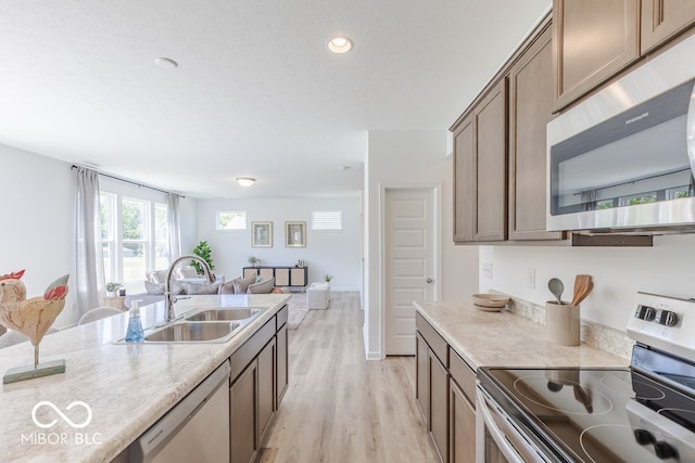 kitchen with stainless steel appliances, light hardwood / wood-style floors, and sink