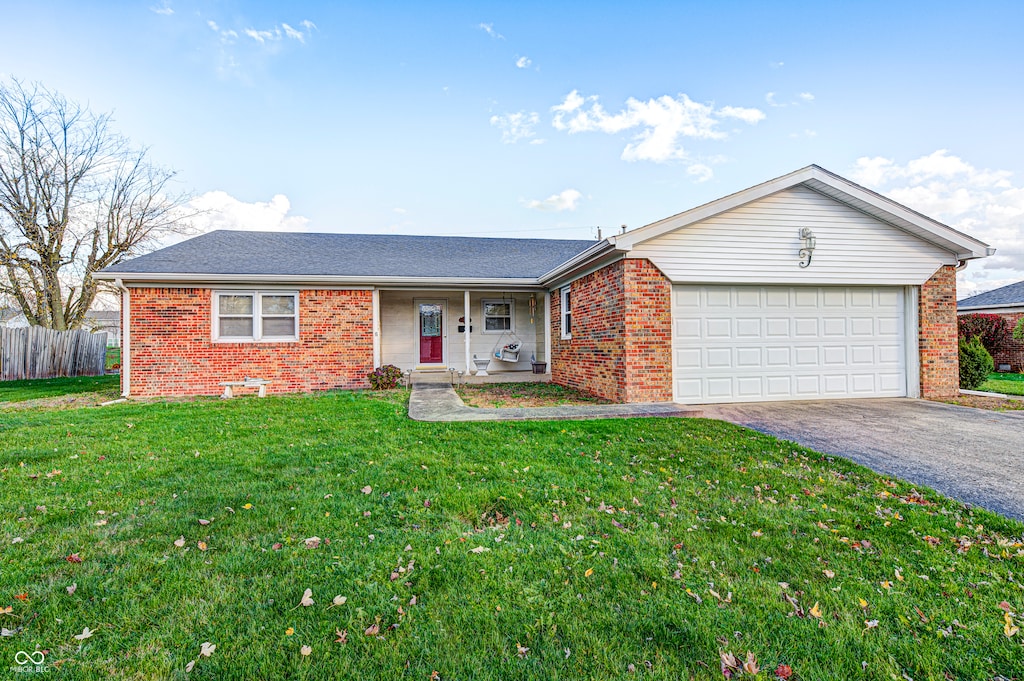 ranch-style house with covered porch, a front yard, and a garage