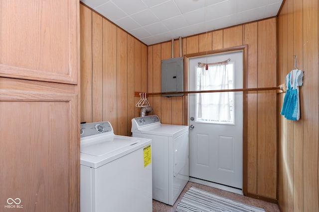 washroom featuring wood walls, electric panel, and washing machine and dryer