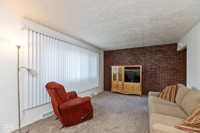 carpeted living room featuring a textured ceiling and brick wall