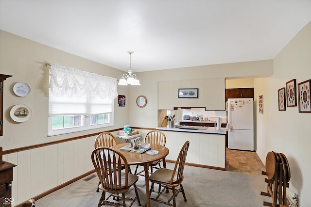 carpeted dining area featuring a chandelier