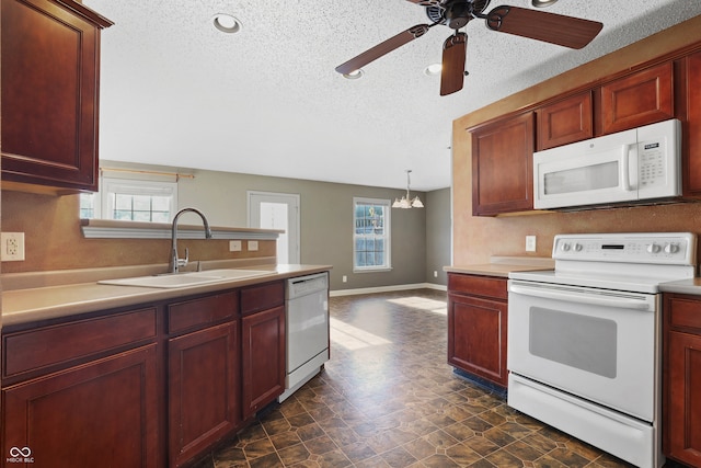 kitchen with ceiling fan with notable chandelier, a textured ceiling, white appliances, sink, and hanging light fixtures