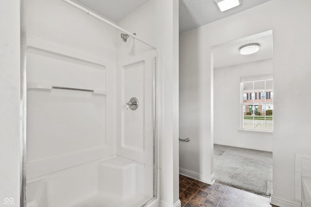 bathroom with a shower with shower door and a textured ceiling