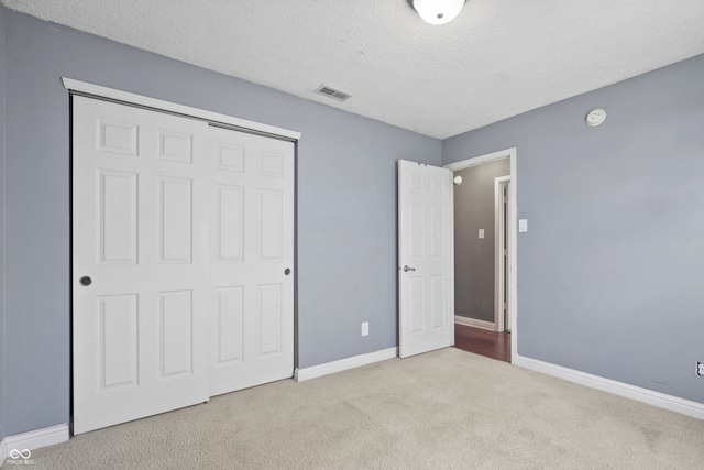 unfurnished bedroom featuring a closet, light colored carpet, and a textured ceiling