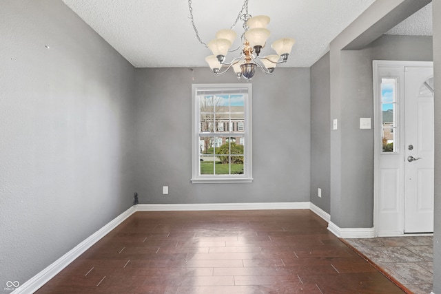 interior space featuring a textured ceiling, dark hardwood / wood-style flooring, and a notable chandelier