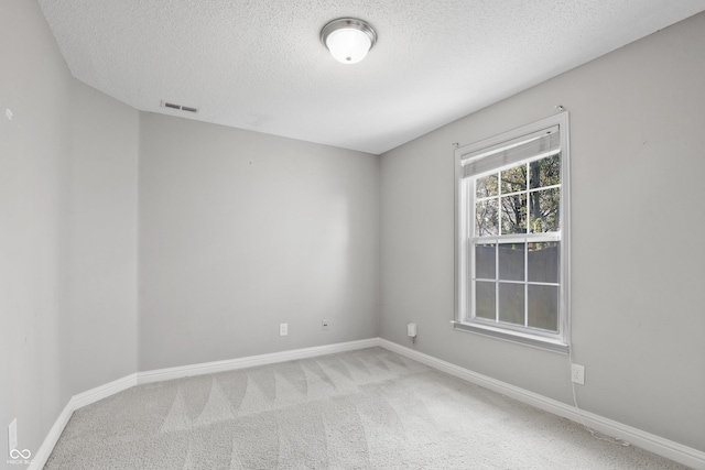 carpeted empty room featuring a textured ceiling