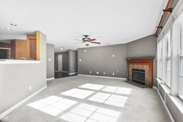 unfurnished living room featuring a textured ceiling, a fireplace, ceiling fan, and light carpet