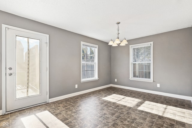 unfurnished dining area featuring a textured ceiling and an inviting chandelier