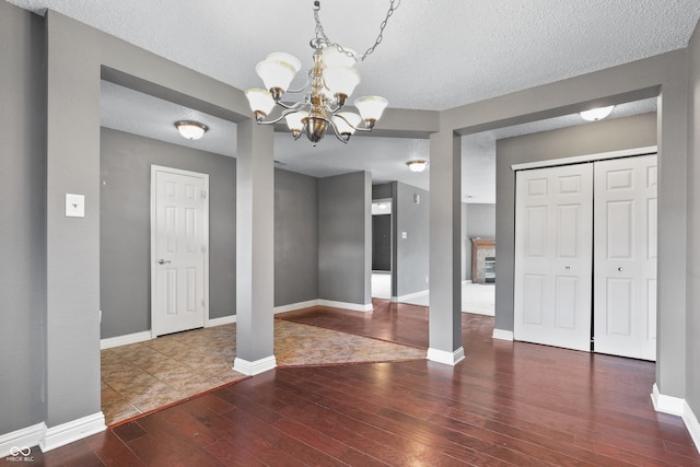 interior space with a textured ceiling, dark hardwood / wood-style floors, and a notable chandelier