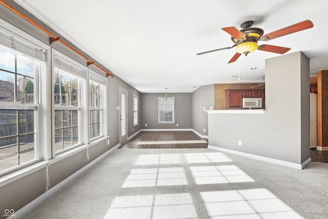 unfurnished living room with a textured ceiling, ceiling fan, and light carpet