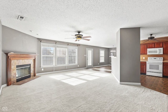 unfurnished living room with a fireplace, a textured ceiling, dark carpet, and a wealth of natural light