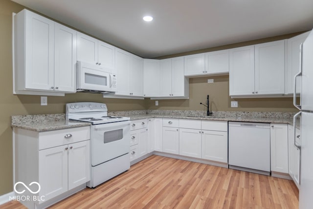 kitchen featuring white appliances, sink, light stone countertops, light hardwood / wood-style floors, and white cabinetry