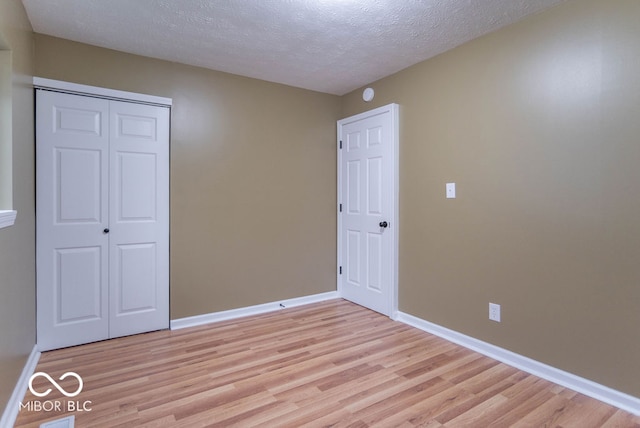 unfurnished bedroom featuring light wood-type flooring, a textured ceiling, and a closet