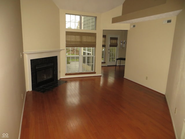 unfurnished living room featuring a fireplace, a high ceiling, and dark wood-type flooring