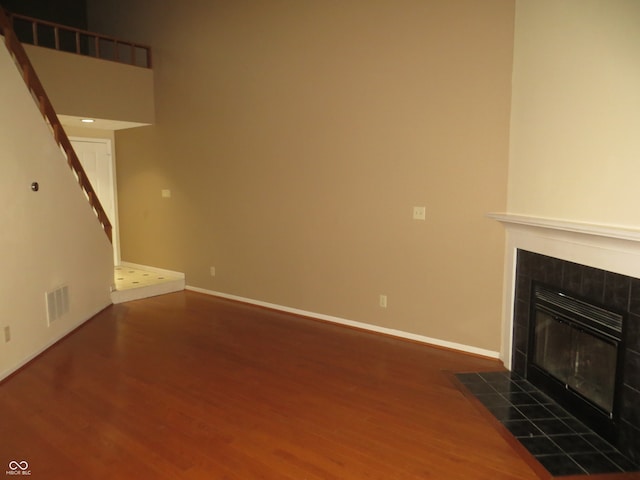 unfurnished living room with dark wood-type flooring and a tiled fireplace